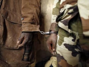 Un prisonnier rebelle menotté à un gendarme malien dans le centre de Tombouctou, le 1er février 2013. REUTERS
