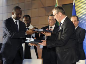 Le commissaire européen au Développement Andris Piebalgs (D) et le ministre des Affaires étrangères malien, Hubert Coulibaly s'échangent les Conventions de financement signées, le 15 mai 2013 à Bruxelles. REUTERS