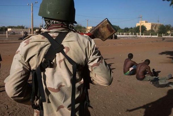 Un soldat malien surveille deux membres présumés du Mujao, le 22 février 2013 à Gao  © AFP