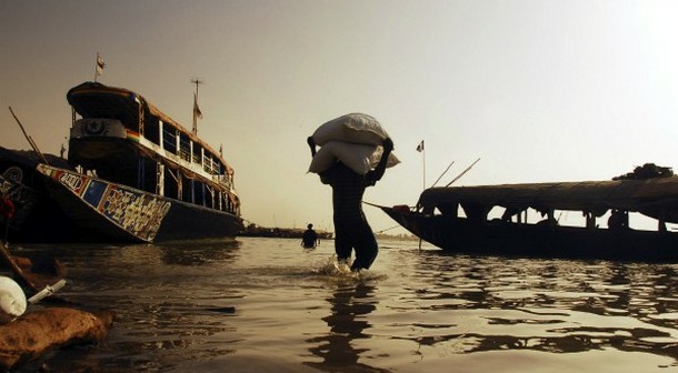 Travailleur portant un sac de céréales à destination d'une pirogue sur le fleuve Niger à Mopti, février 2007, REUTERS