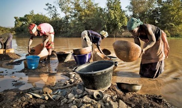 Traditionnellement, ce sont les femmes, courbées en deux, qui lavent le sable aurifère dans les eaux boueuses de la rivière. Crédits photo : Stephen Dock / Agence VU