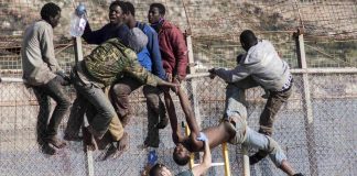 Les gardes civils espagnols tentent de déloger des migrants assis sur le grillage, frontière entre le Maroc et l’enclave de Ceuta