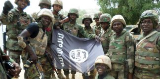 Des soldats nigérians posent devant le drapeau de Boko Haram après avoir démantelé un camp de la secte armée dans l'Etat du Yobe, en février dernier. © AFP PHOTO/HO/NIGERIAN ARMY