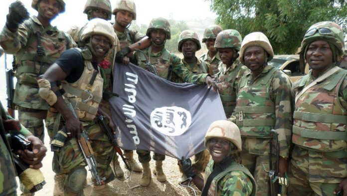 Des soldats nigérians posent devant le drapeau de Boko Haram après avoir démantelé un camp de la secte armée dans l'Etat du Yobe, en février dernier. © AFP PHOTO/HO/NIGERIAN ARMY