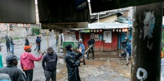 Un policier lève son arme pour disperser des opposants qui tentent de bloquer l'accès aux bureaux de vote, le 26 octobre 2017 dans le quartier de Mathare, à Nairobi / © AFP / MARCO LONGARI