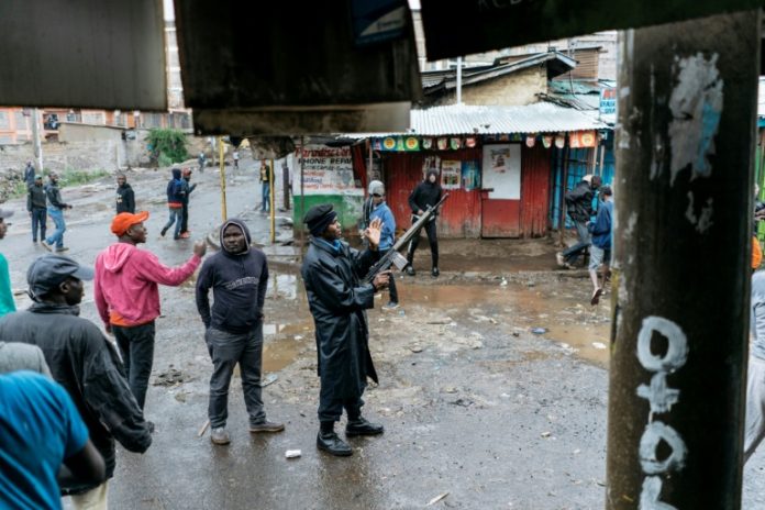 Un policier lève son arme pour disperser des opposants qui tentent de bloquer l'accès aux bureaux de vote, le 26 octobre 2017 dans le quartier de Mathare, à Nairobi / © AFP / MARCO LONGARI