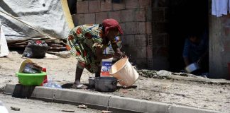 Une femme d’origine subsaharienne fait la vaisselle devant un bâtiment en construction occupé par des migrants, à Alger, en mai 2016